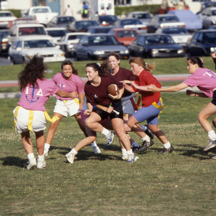 Group of six women playing football on the grass